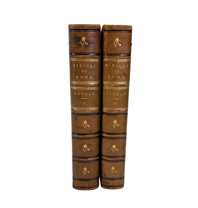 Two antique leather-bound books standing upright side by side on a white background. The spines are brown with gold lettering and decorative bands, and the titles read 'History of Rome' and 'Arnold III'.