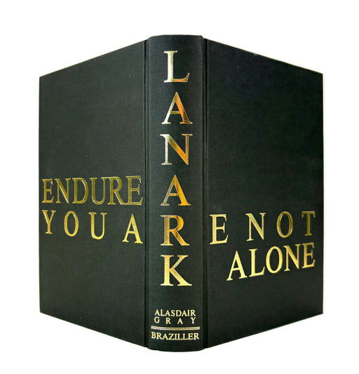 A hardcover book shown at a three-quarter angle on a white background, featuring a black cover with gold foil lettering. The spine displays the title 'LANARK' vertically, and the front cover shows 'ENDURE YOU ARE NOT ALONE'.