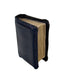 A miniature black faux-leather book cover or miniature book with textured black faux leather on the front and spine, showing aged beige pages, set against a plain white background.