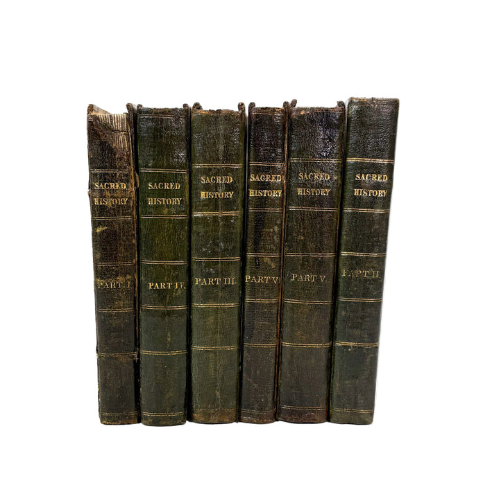 A set of six antique leather-bound books standing upright against a plain white background. The spines are dark brown and greenish-black with gold lettering reading 'SACRED HISTORY' and section titles like 'PART I', 'PART II', and 'PART III'.