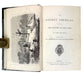 An open vintage book showing the title page of 'The Golden Americas' by John Tillotson, with a black-and-white illustration on the left page and printed text on the right page, photographed against a light background.