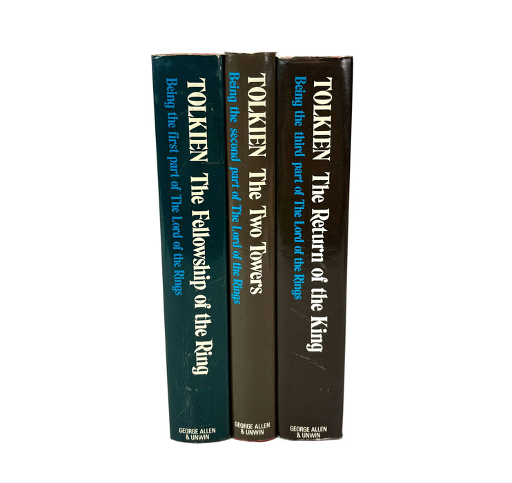 Three hardcover books standing upright on a white background, showing their dark blue, brown, and dark brown spines with white text. The titles visible are Tolkien: The Fellowship of the Ring, Tolkien: The Two Towers, and Tolkien: The Return of the King, with George Allen & Unwin branding at the bottom.