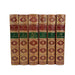 A set of eight hardcover books from the 'Novels of Geo. Eliot' series, bound in dark reddish-brown leather with ornate gold gilding and green title bands, displayed upright against a plain white background.