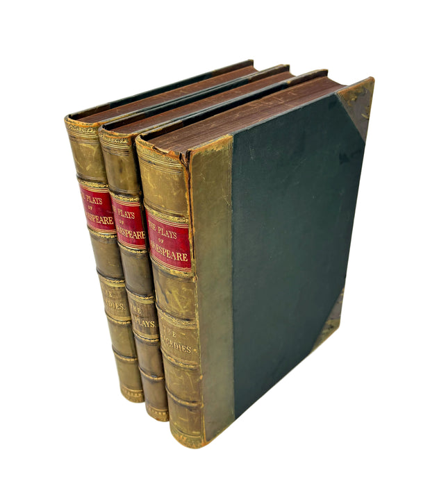 A set of three antique hardcover books standing upright, showing their brown leather-spined covers with red and gold title bands, alongside a dark green cloth-lean side, photographed on a white background.