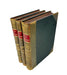 A set of three antique hardcover books standing upright, showing their brown leather-spined covers with red and gold title bands, alongside a dark green cloth-lean side, photographed on a white background.