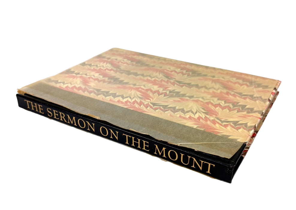 A vintage hardcover book titled 'THE SERMON ON THE MOUNT' with a marbled patterned cover in beige, pink, and brown tones, and a black spine with gold lettering, photographed on a white background.