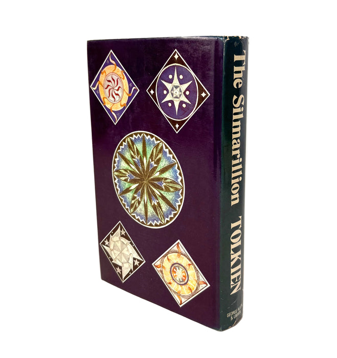 A hardcover book titled 'The Silmarillion' by Tolkien, featuring a deep purple cover decorated with intricate multicolor circular and diamond motifs, set against a plain white background.