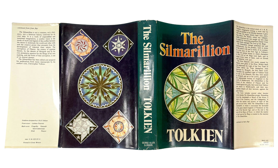 An open hardcover book showing the front cover, spine, and inner pages of 'The Silmarillion' by Tolkien. The cover features a dark green background with a large multicolored circular emblem and the title in orange and white text.