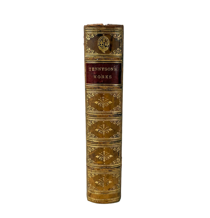 A vintage hardcover book standing upright, showing its decorative spine with gold embossed floral patterns and a central dark red label reading 'Tennyson's Works'.