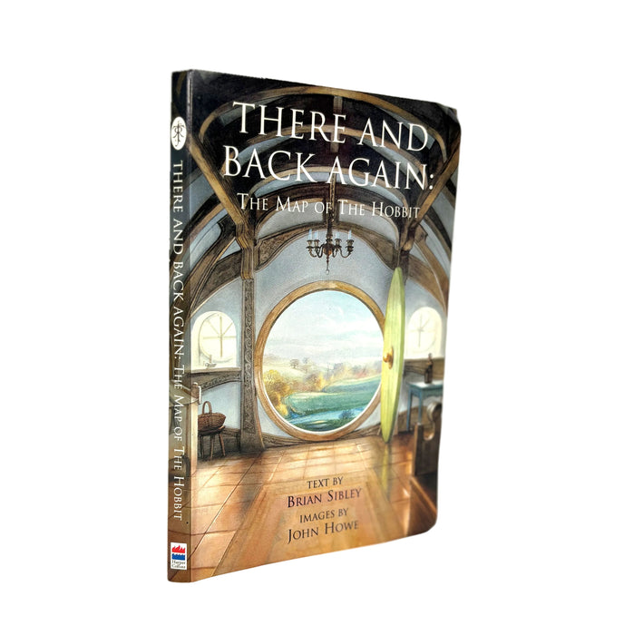 A hardcover book titled 'There and Back Again: The Map of the Hobbit' standing upright at a slight angle on a white background. The cover features an illustration of an interior scene with a large circular window showing a landscape and a boat on the water.